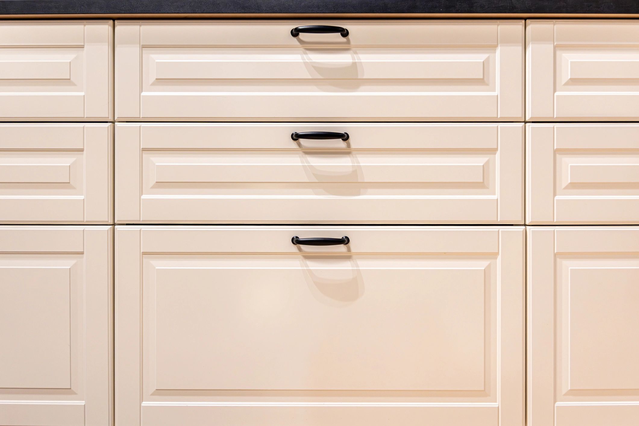 Cream-colored kitchen drawers with black handles