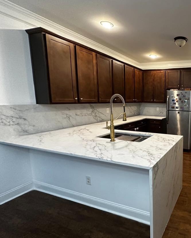 Marble-look peninsula with dark wood cabinets
