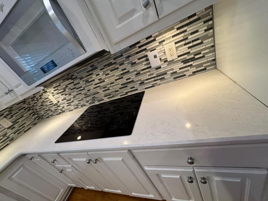 Marble-look countertop with induction cooktop and mosaic backsplash